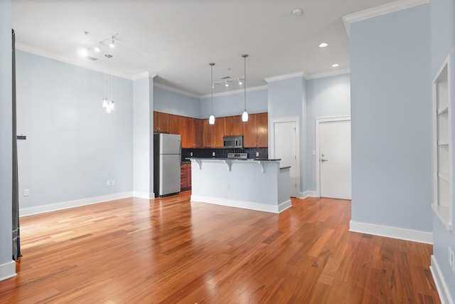 kitchen featuring appliances with stainless steel finishes, hanging light fixtures, light hardwood / wood-style floors, and a breakfast bar area