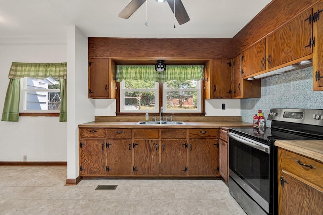 kitchen with a healthy amount of sunlight, stainless steel range with electric stovetop, sink, and ceiling fan