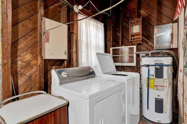 clothes washing area featuring wood walls, electric water heater, and washing machine and dryer