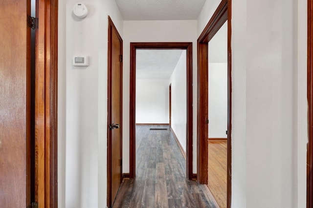 corridor featuring a textured ceiling and dark hardwood / wood-style floors