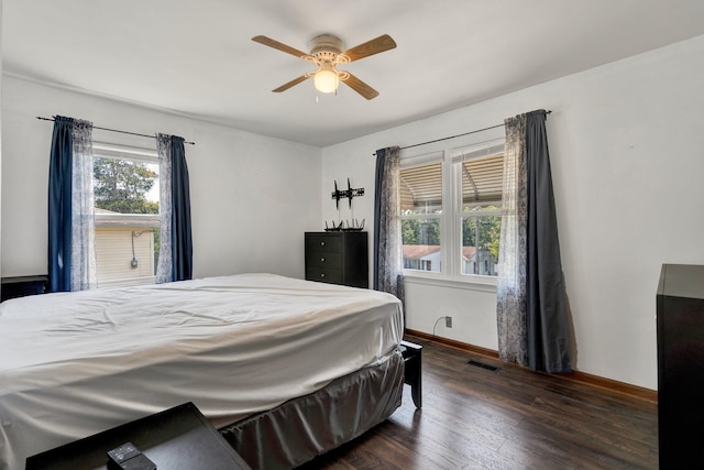 bedroom featuring multiple windows, dark hardwood / wood-style floors, and ceiling fan