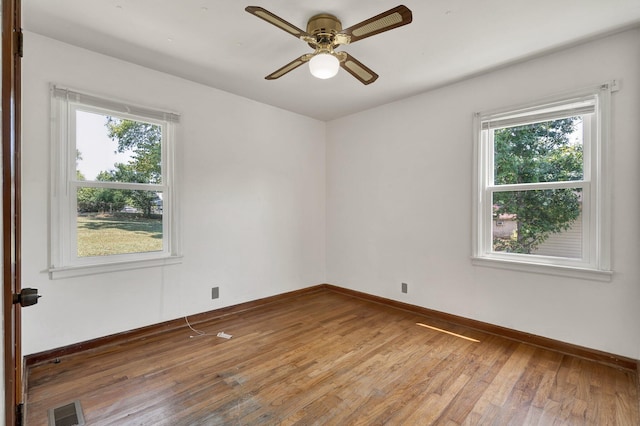 spare room featuring ceiling fan, hardwood / wood-style flooring, and plenty of natural light