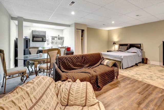 bedroom with a paneled ceiling and light hardwood / wood-style floors