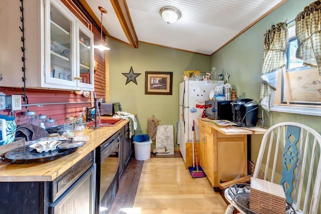 kitchen with wooden counters, decorative light fixtures, light hardwood / wood-style flooring, black dishwasher, and vaulted ceiling