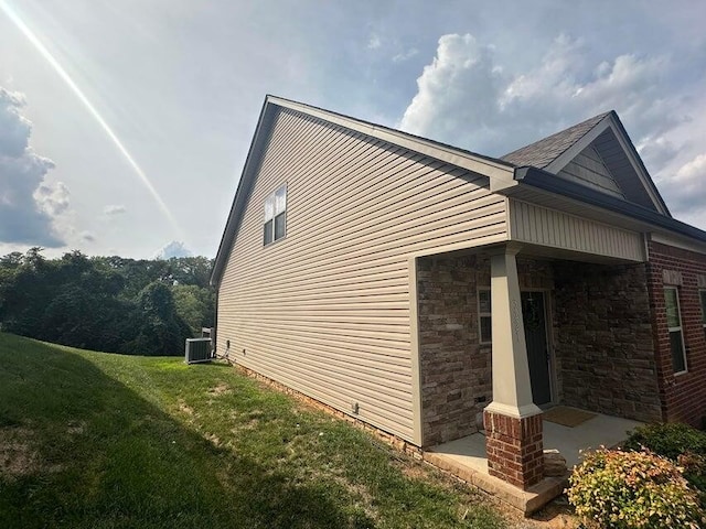 view of property exterior with a lawn and central air condition unit