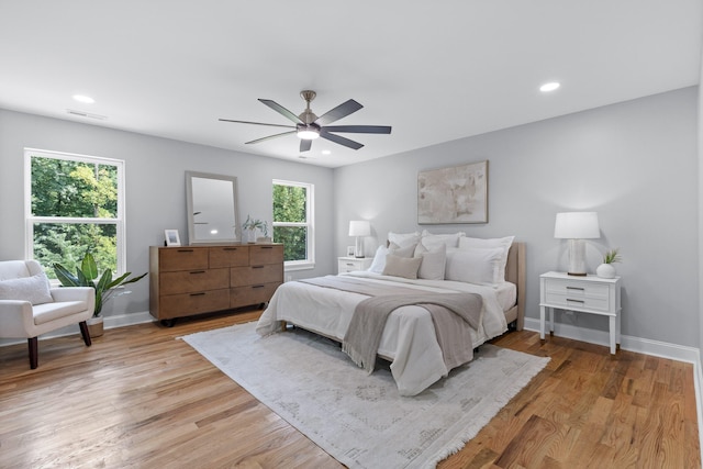 bedroom with light wood-type flooring, ceiling fan, and multiple windows