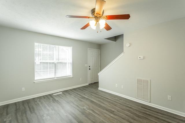 empty room with ceiling fan, dark hardwood / wood-style floors, and a textured ceiling