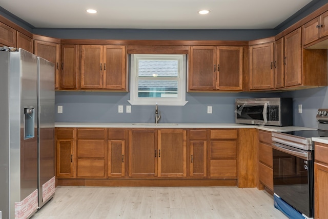 kitchen featuring stainless steel appliances, light wood-type flooring, and sink