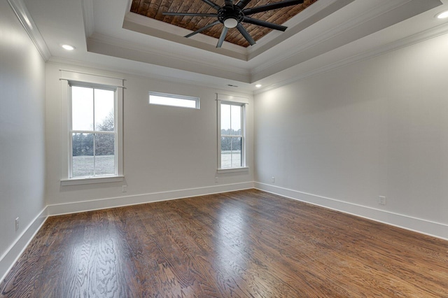 empty room featuring dark wood-type flooring, a tray ceiling, ceiling fan, and crown molding