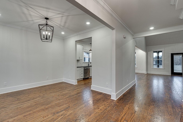 unfurnished room featuring a healthy amount of sunlight, sink, crown molding, and an inviting chandelier