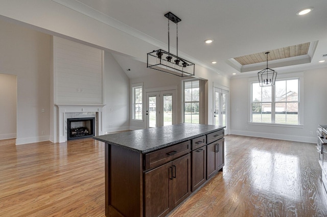 kitchen featuring french doors, a kitchen island, a raised ceiling, hanging light fixtures, and light hardwood / wood-style floors