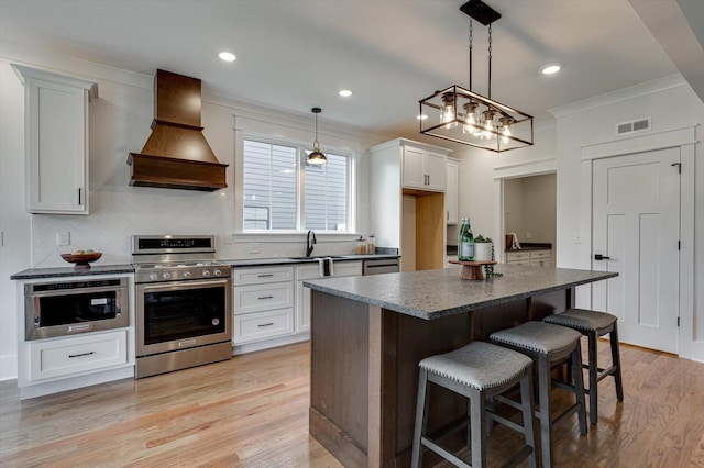 105 Arthur Ln, Cleveland, TN 37312 - kitchen with appliances with stainless steel finishes, custom range hood, dark countertops, ornamental molding, and a kitchen bar