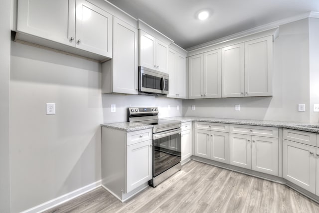 kitchen featuring white cabinets, appliances with stainless steel finishes, light wood-type flooring, and light stone countertops