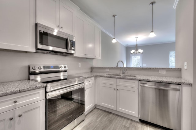 kitchen with sink, white cabinets, an inviting chandelier, stainless steel appliances, and ornamental molding