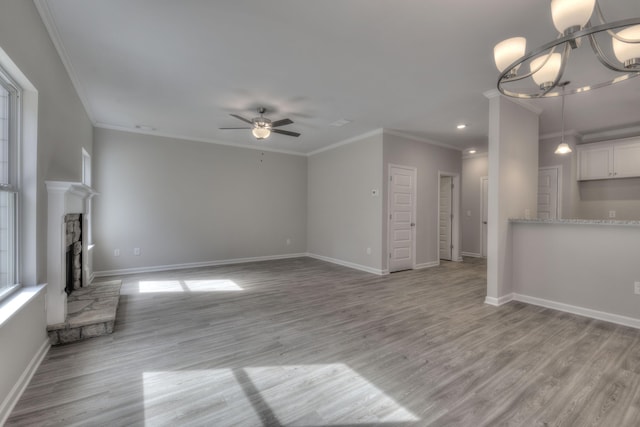 unfurnished living room with crown molding, ceiling fan with notable chandelier, light hardwood / wood-style floors, and a fireplace