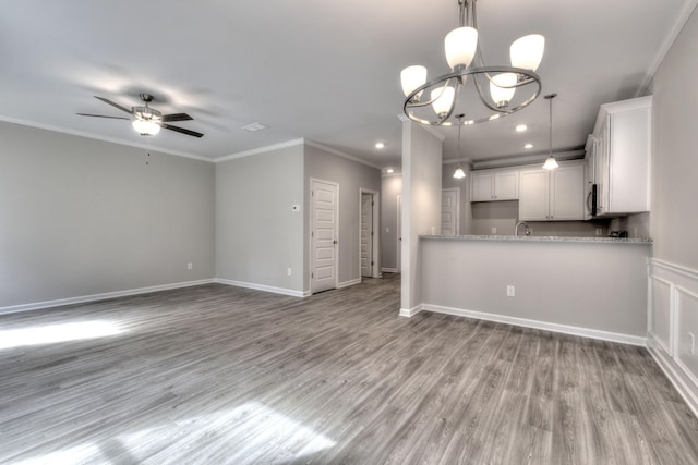 kitchen with white cabinets, light stone countertops, ceiling fan with notable chandelier, crown molding, and light hardwood / wood-style floors