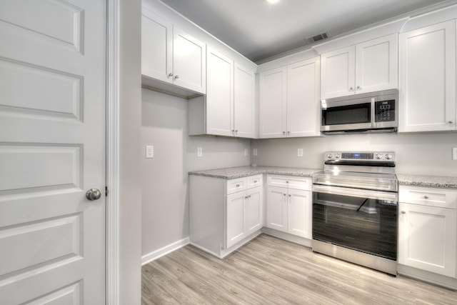 kitchen with appliances with stainless steel finishes, white cabinetry, light hardwood / wood-style flooring, and light stone counters