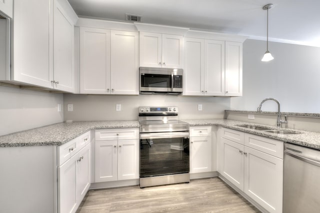 kitchen featuring light hardwood / wood-style floors, sink, white cabinetry, stainless steel appliances, and decorative light fixtures