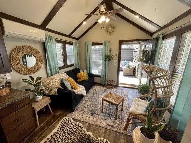 living area featuring high vaulted ceiling, dark hardwood / wood-style flooring, beam ceiling, ceiling fan, and a wall mounted air conditioner