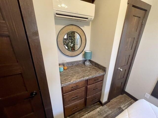 bathroom featuring wood-type flooring, vanity, and a wall mounted AC