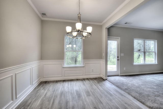 unfurnished dining area with a notable chandelier, light hardwood / wood-style flooring, plenty of natural light, and ornamental molding