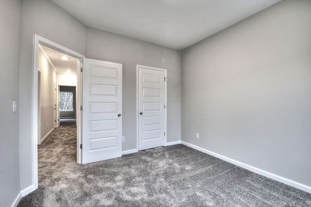 unfurnished bedroom featuring dark carpet and a closet