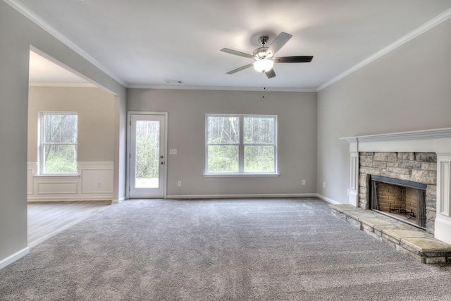 unfurnished living room featuring ceiling fan, a stone fireplace, light carpet, and ornamental molding