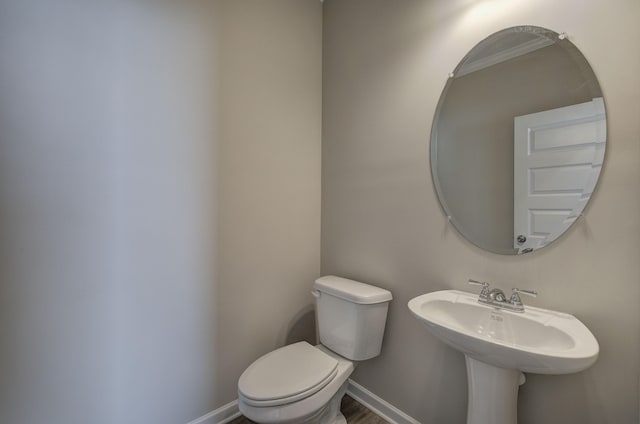 bathroom featuring ornamental molding, hardwood / wood-style floors, and toilet