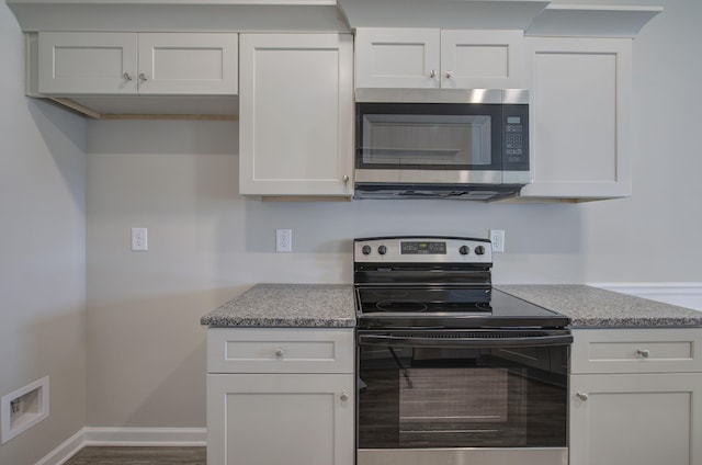 kitchen featuring stainless steel appliances, white cabinetry, and dark wood-type flooring