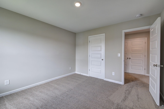 unfurnished bedroom with light colored carpet and a closet