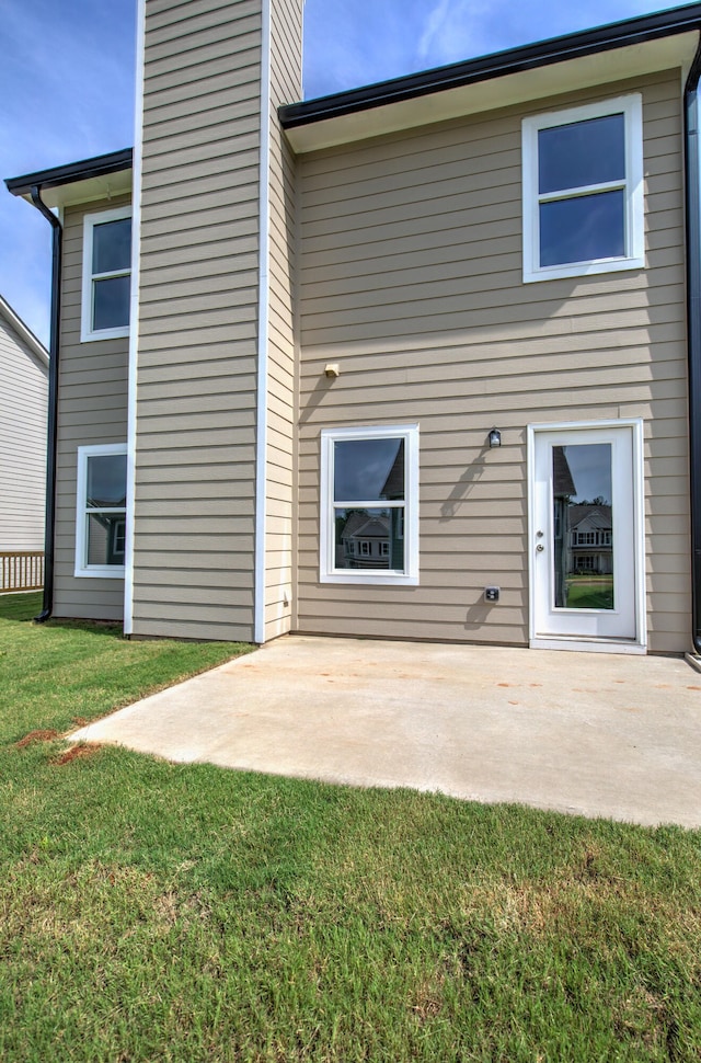 rear view of property featuring a yard and a patio area