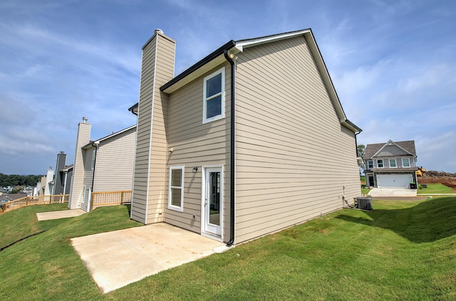 rear view of property featuring a garage, a yard, a patio area, and central air condition unit