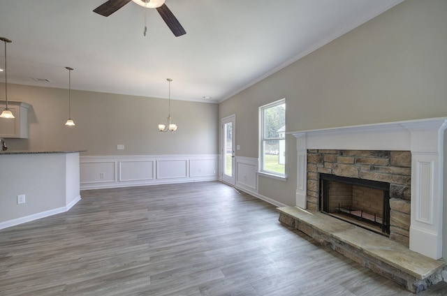 unfurnished living room featuring ceiling fan with notable chandelier, a fireplace, hardwood / wood-style flooring, ornamental molding, and sink