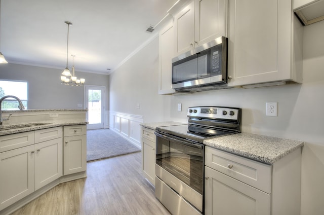 kitchen featuring light stone counters, stainless steel appliances, light hardwood / wood-style flooring, ornamental molding, and a chandelier