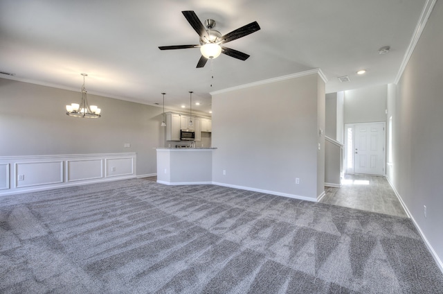 unfurnished living room with ceiling fan with notable chandelier, carpet, and crown molding