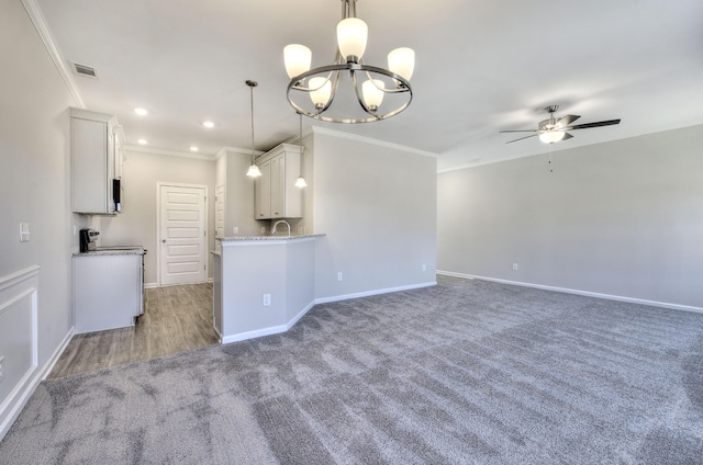 kitchen with white cabinets, ceiling fan with notable chandelier, pendant lighting, and ornamental molding