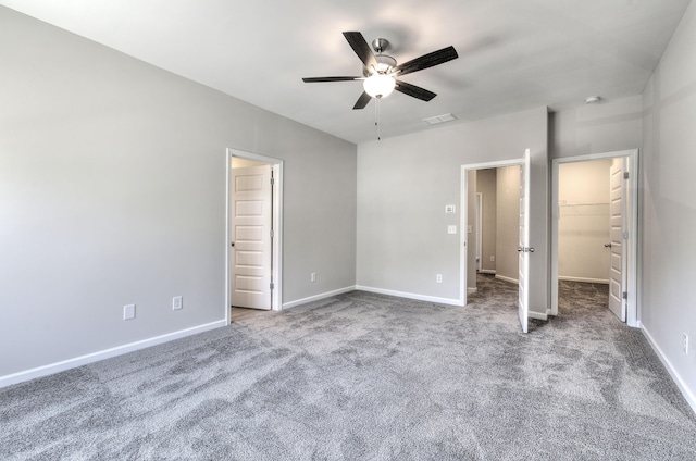 unfurnished bedroom featuring carpet floors, a spacious closet, ceiling fan, and a closet