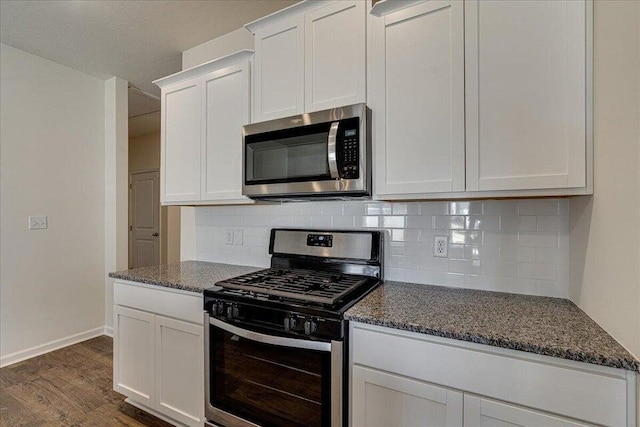 kitchen featuring dark stone counters, dark hardwood / wood-style floors, white cabinets, stainless steel appliances, and backsplash