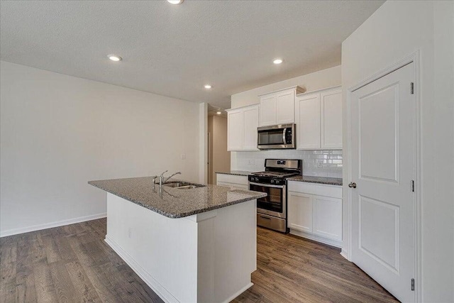 kitchen featuring white cabinetry, dark hardwood / wood-style flooring, stainless steel appliances, a kitchen island with sink, and sink