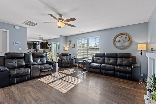 living room with a textured ceiling, dark wood-type flooring, and ceiling fan