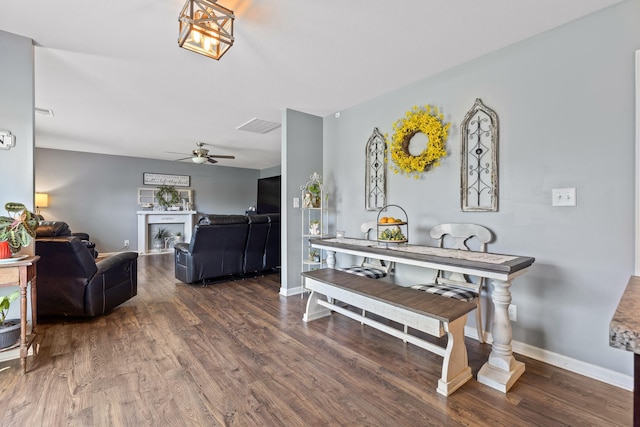 dining area featuring ceiling fan, a fireplace, and dark hardwood / wood-style floors