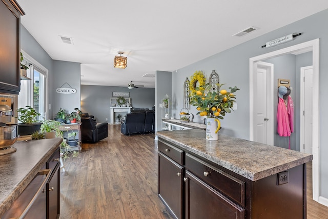 kitchen with dark brown cabinets, ceiling fan, dark hardwood / wood-style floors, and a kitchen island