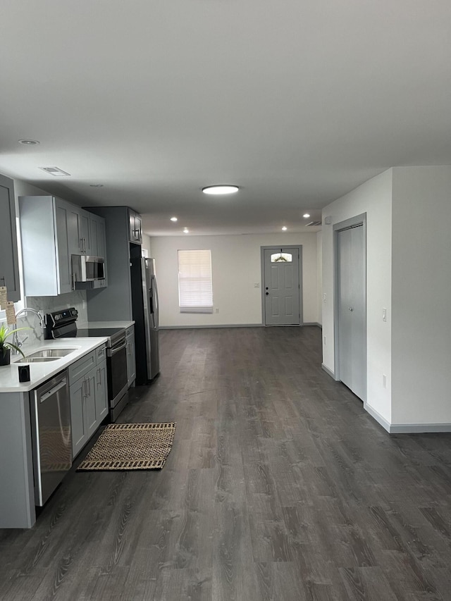 kitchen featuring tasteful backsplash, sink, gray cabinetry, appliances with stainless steel finishes, and dark hardwood / wood-style flooring