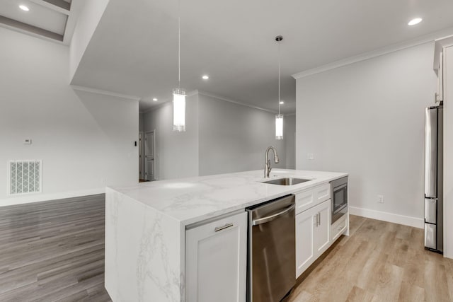 kitchen featuring white cabinets, hanging light fixtures, sink, a center island with sink, and stainless steel appliances