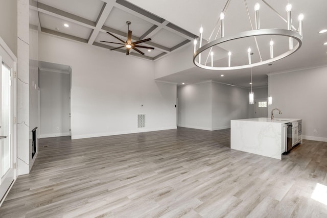 unfurnished living room featuring ceiling fan with notable chandelier, light wood-type flooring, a fireplace, and a healthy amount of sunlight