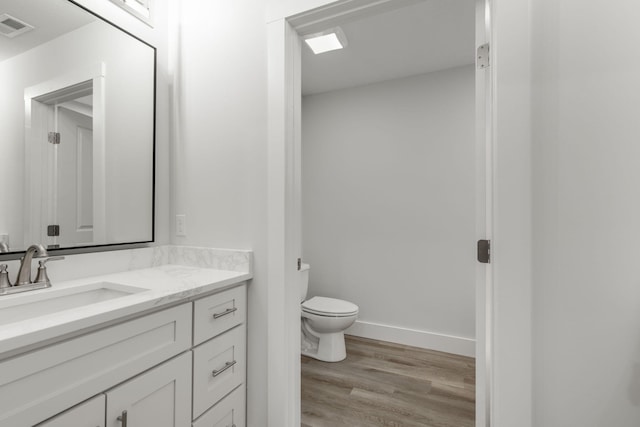 bathroom featuring wood-type flooring, vanity, and toilet