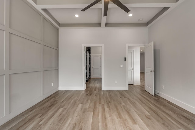 unfurnished bedroom featuring a closet, light hardwood / wood-style floors, ceiling fan, and beamed ceiling