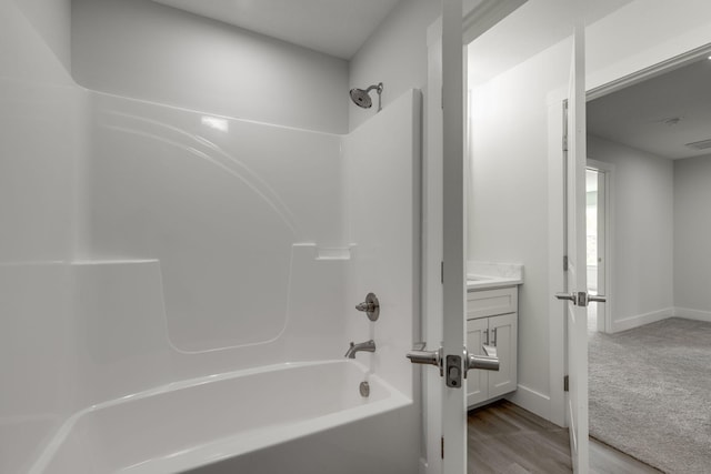 bathroom with wood-type flooring, shower / washtub combination, and vanity