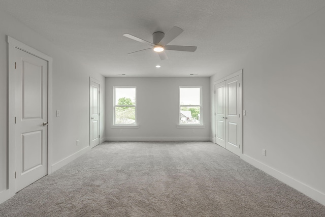 unfurnished room featuring ceiling fan, light colored carpet, and a textured ceiling