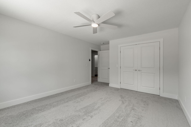 unfurnished bedroom featuring ceiling fan, a closet, and light carpet